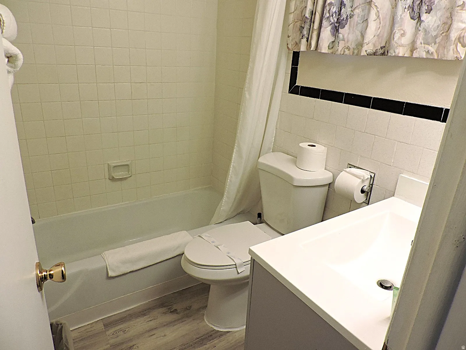 Full bathroom featuring tile walls, dark wood-style floors, vanity, and shower / bathtub combination with curtain