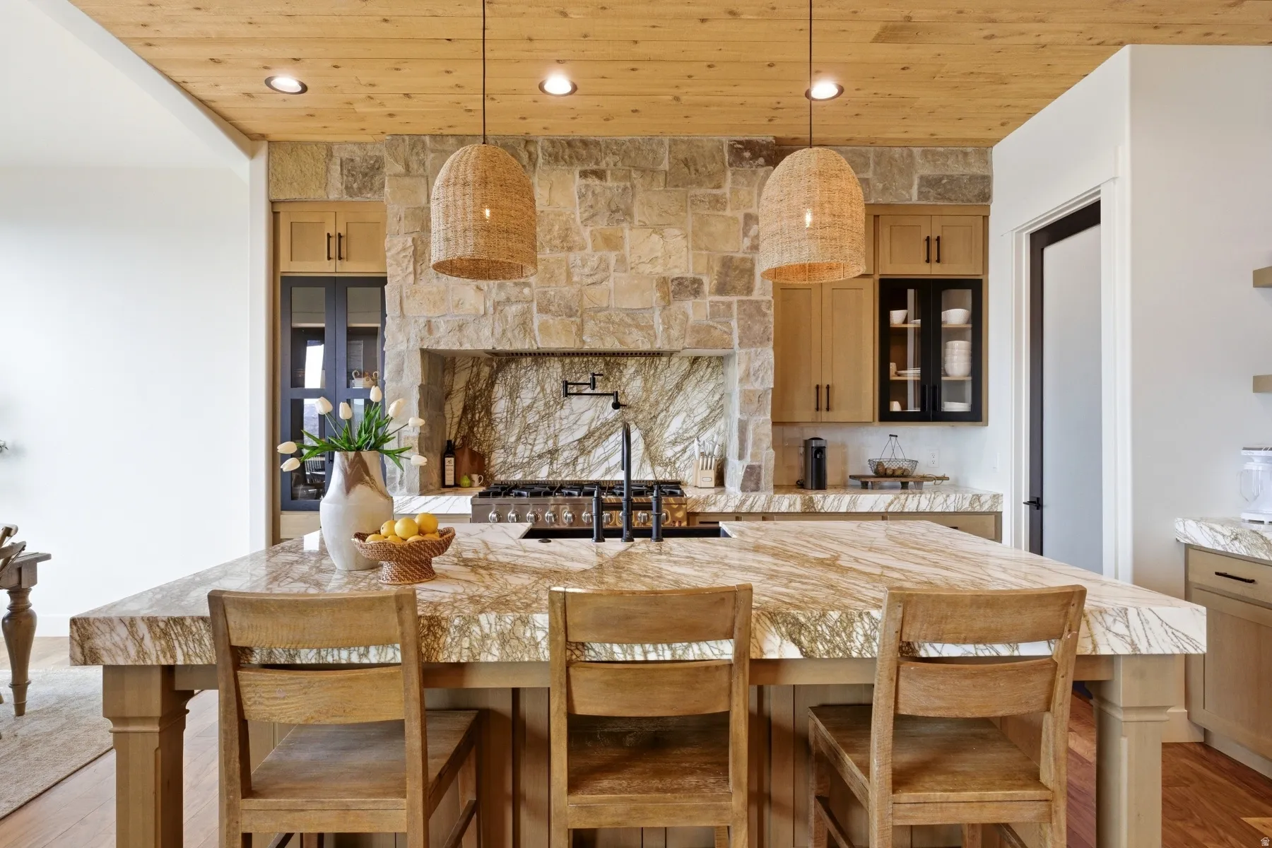 Kitchen featuring light stone counters, light wood finished floors, light wood finish cabinets, a breakfast bar area, and wood ceiling