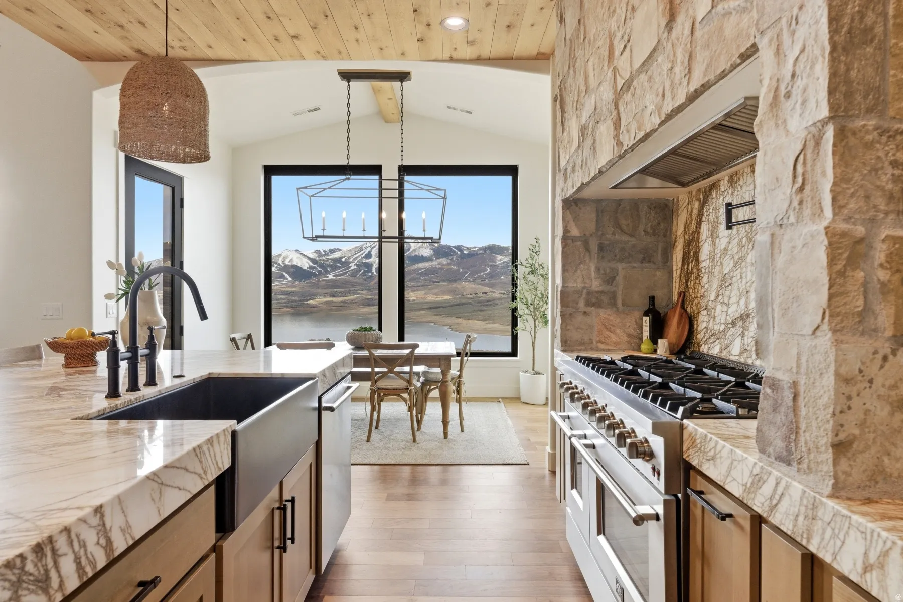 Kitchen featuring wood finish cabinetry, light wood-type flooring, double oven range, healthy amount of natural light, and beamed ceiling