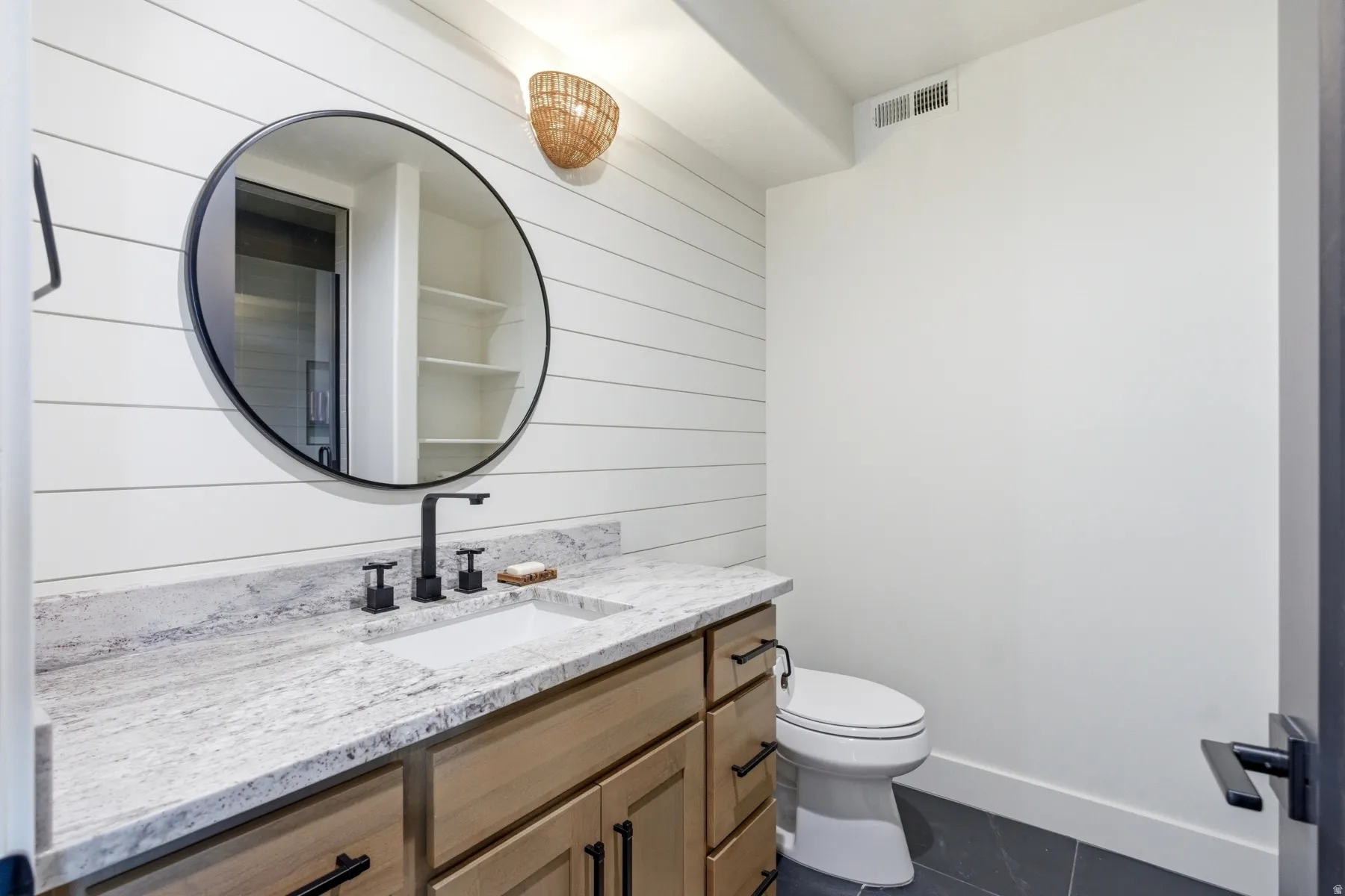 Bathroom featuring vanity, dark tile patterned flooring, and wooden walls