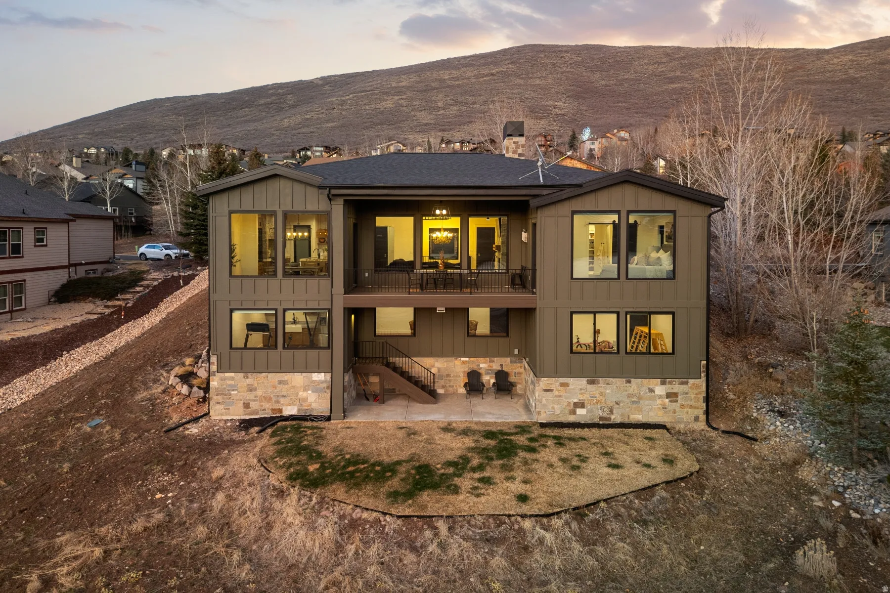 Rear view of property featuring board and batten siding, a patio, a balcony, a mountain view, and stone siding