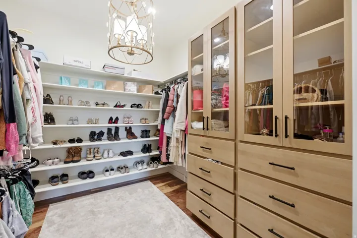 Walk in closet with a chandelier and light wood-type flooring