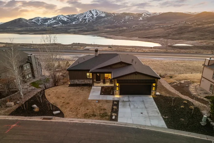 View of front facade featuring board and batten siding, a mountain view, concrete driveway, stone siding, and roof with shingles