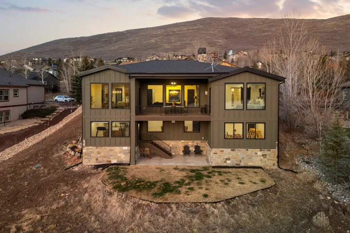 Rear view of property featuring board and batten siding, a patio, a balcony, a mountain view, and stone siding