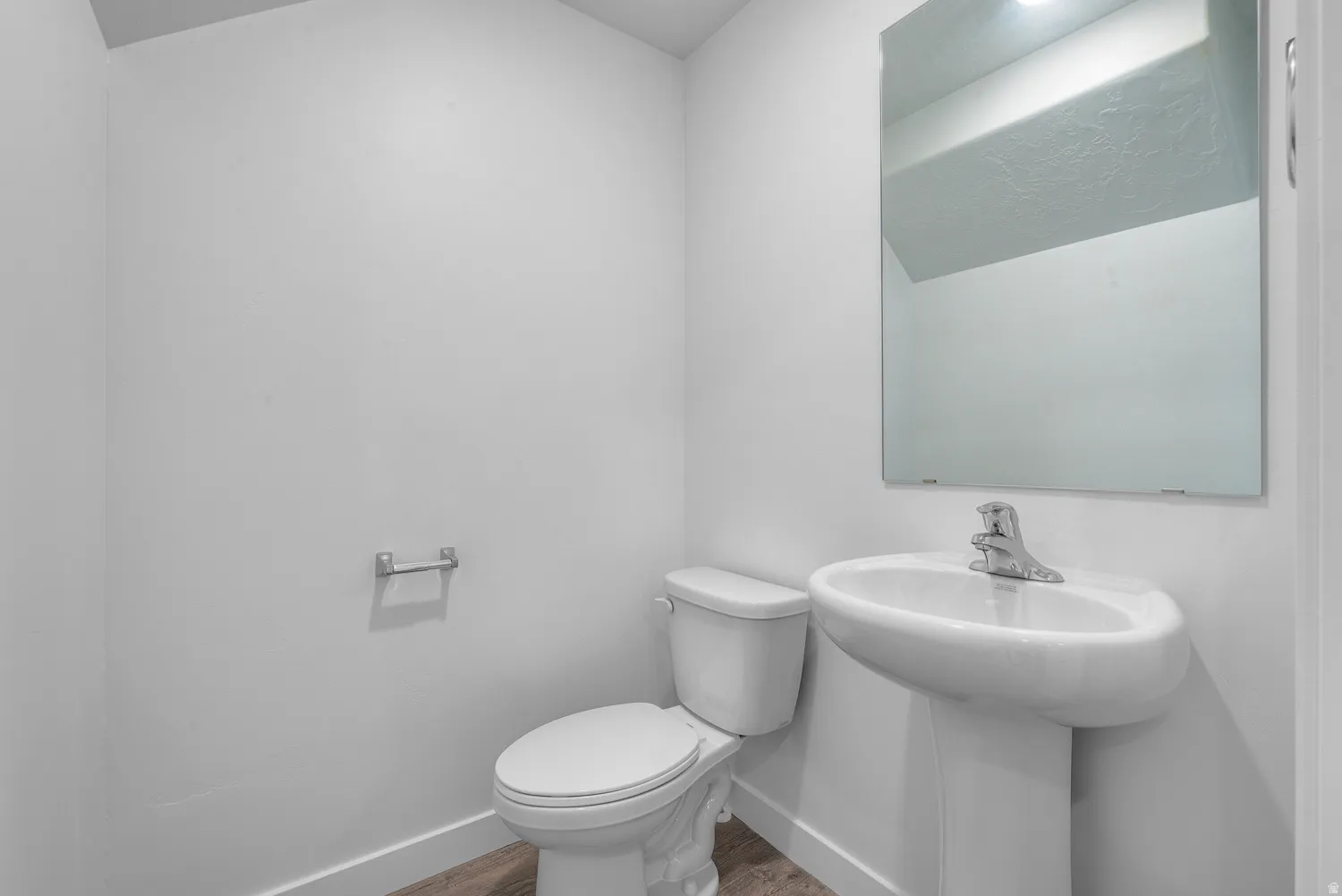 Half bath with toilet and wood finished floors