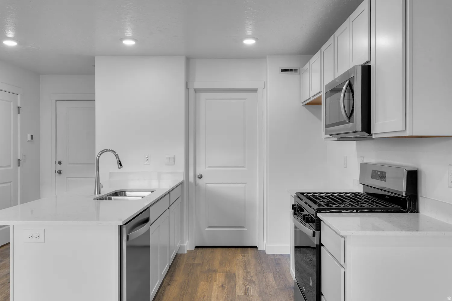 Kitchen with stainless steel appliances, light stone counters, a peninsula, dark wood-style flooring, and recessed lighting