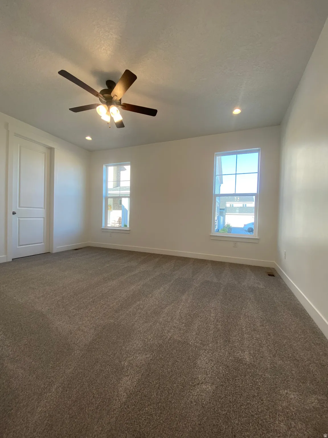 Empty room featuring dark carpet, healthy amount of natural light, a textured ceiling, ceiling fan, and recessed lighting*Photos are for reference only and are not of specific unit listed.  Finishes may differ from pictures shown.