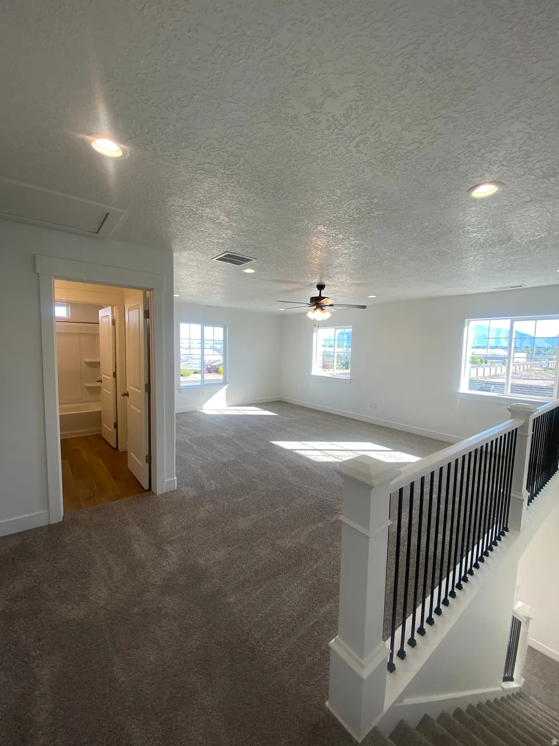 Empty room with dark colored carpet, recessed lighting, a textured ceiling, and a ceiling fan*Photos are for reference only and are not of specific unit listed.  Finishes may differ from pictures shown.