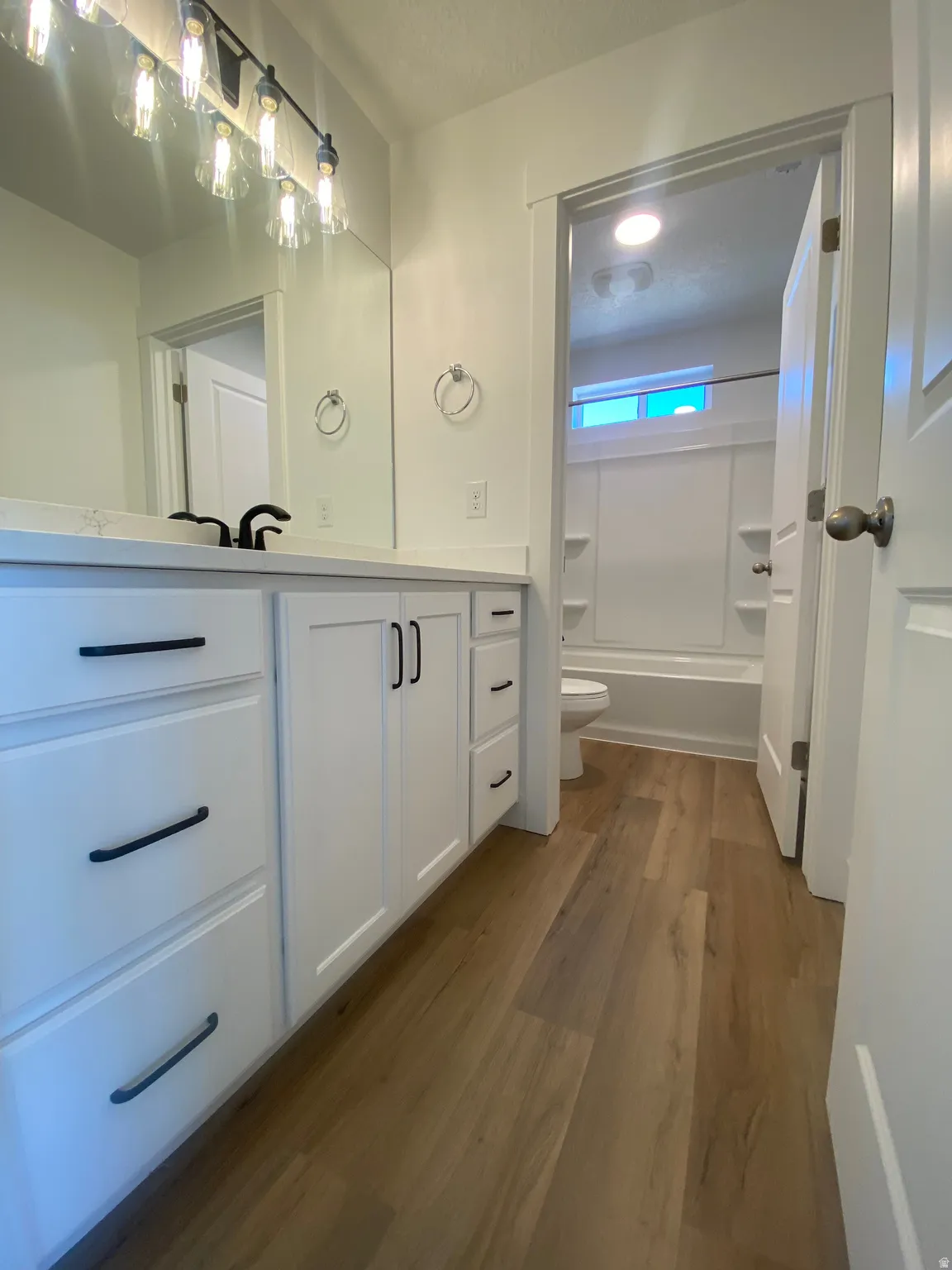 Bathroom with vanity, dark wood finished floors, and bathing tub / shower combination*Photos are for reference only and are not of specific unit listed.  Finishes may differ from pictures shown.