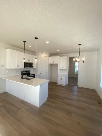 Kitchen featuring a peninsula, stainless steel appliances, white cabinets, dark wood-style floors, and a chandelier*Photos are for reference only and are not of specific unit listed.  Finishes may differ from pictures shown.