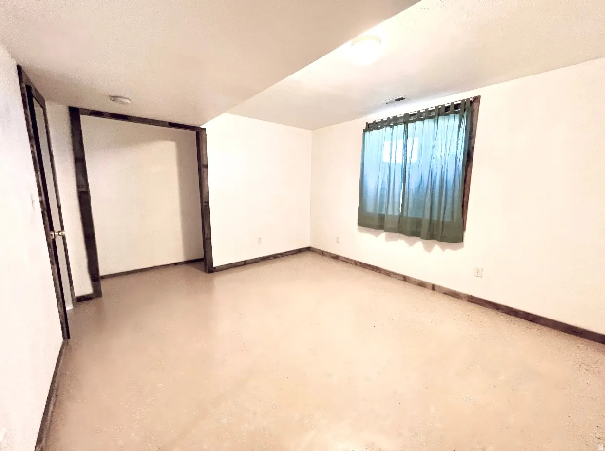 Empty room featuring concrete flooring and baseboards