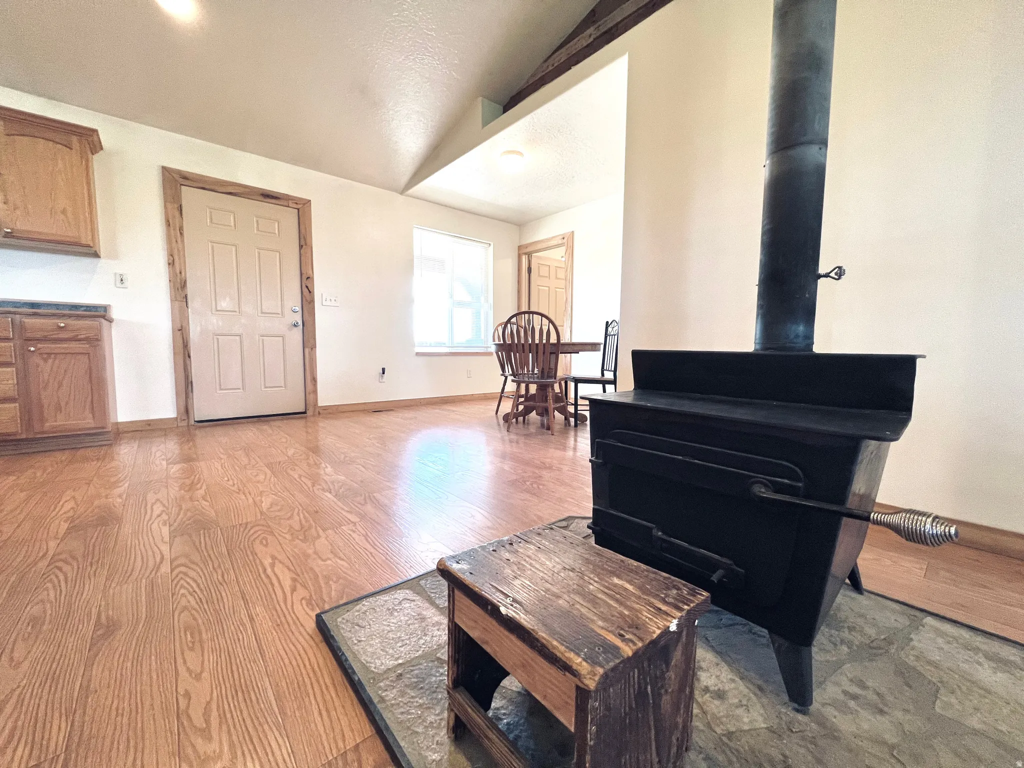 Living area featuring a wood stove, lofted ceiling, and light wood finished floors