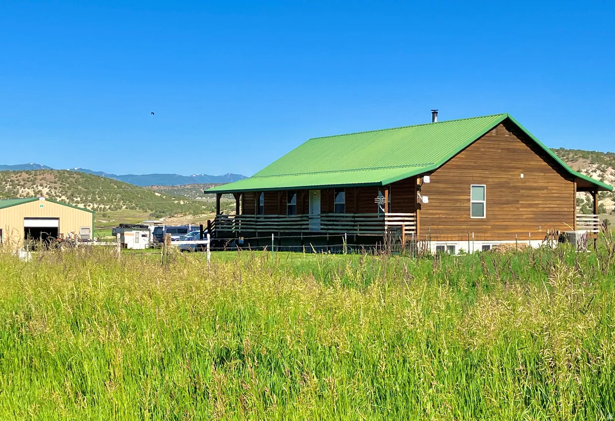 Back of house featuring a mountain view, a metal roof, an outbuilding, and a detached garage