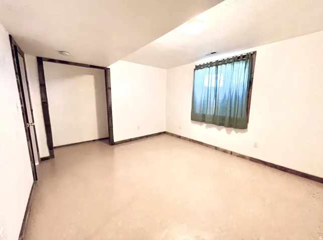 Empty room featuring concrete flooring and baseboards