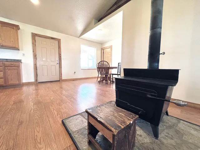 Living area featuring a wood stove, lofted ceiling, and light wood finished floors