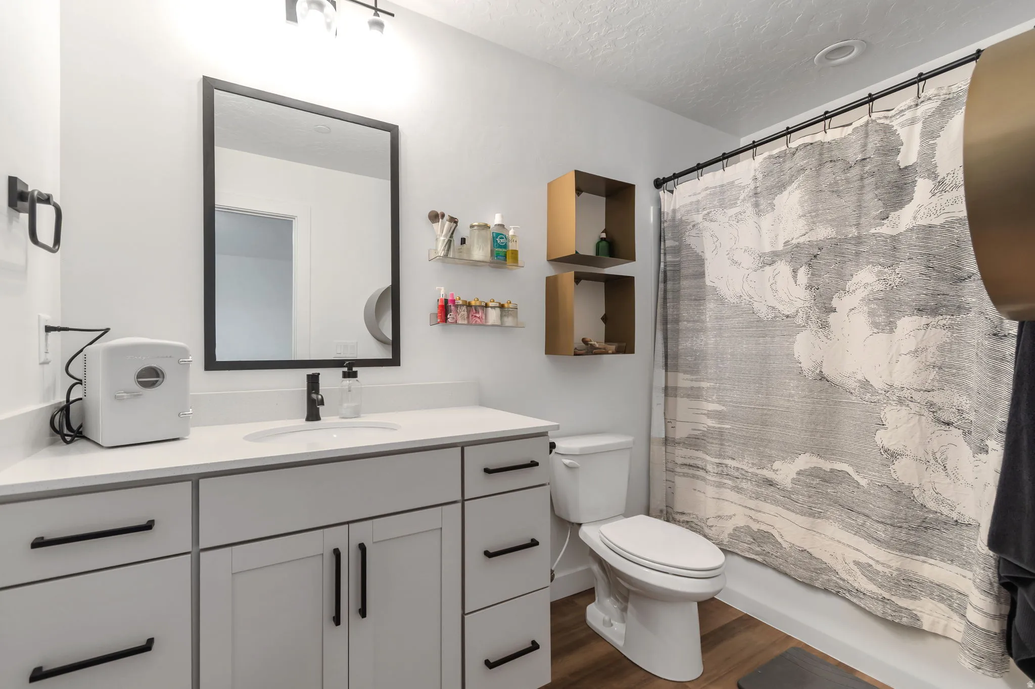 Full bath featuring vanity, dark wood-style flooring, and a textured ceiling
