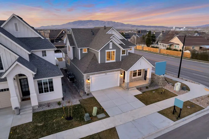 View of front of property with board and batten siding, roof with shingles, driveway, a garage, and a residential view