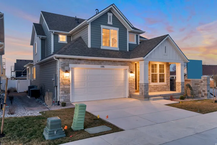 View of front of property with stone siding, a shingled roof, a porch, and concrete driveway