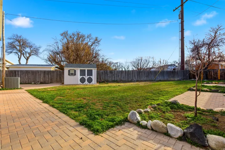 Fenced backyard featuring a shed