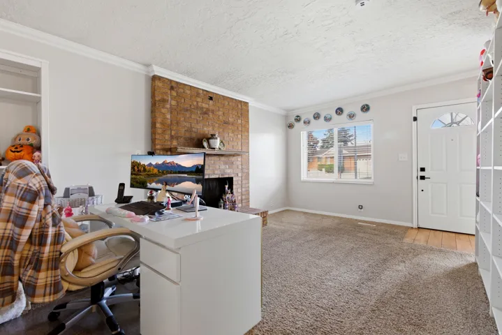 Office featuring light carpet, a fireplace, a textured ceiling, and crown molding