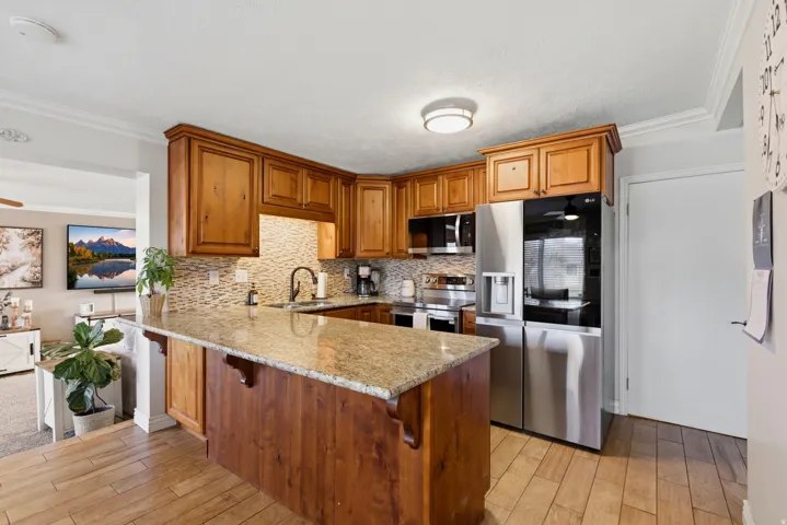 Kitchen with a peninsula, ornamental molding, wood finish cabinetry, stainless steel appliances, and a ceiling fan