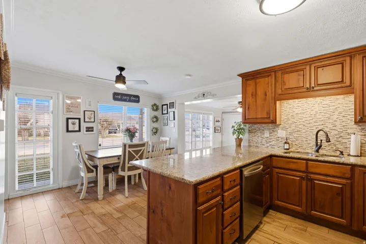 Kitchen featuring light stone counters, wood tiled floors, wood finish cabinets, a peninsula, and ornamental molding