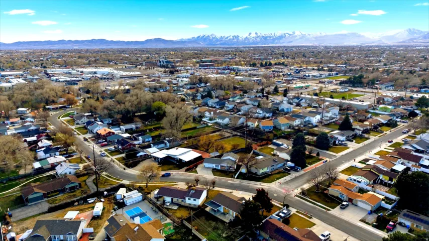 Aerial view of property and surrounding area featuring a mountainous background and nearby suburban area