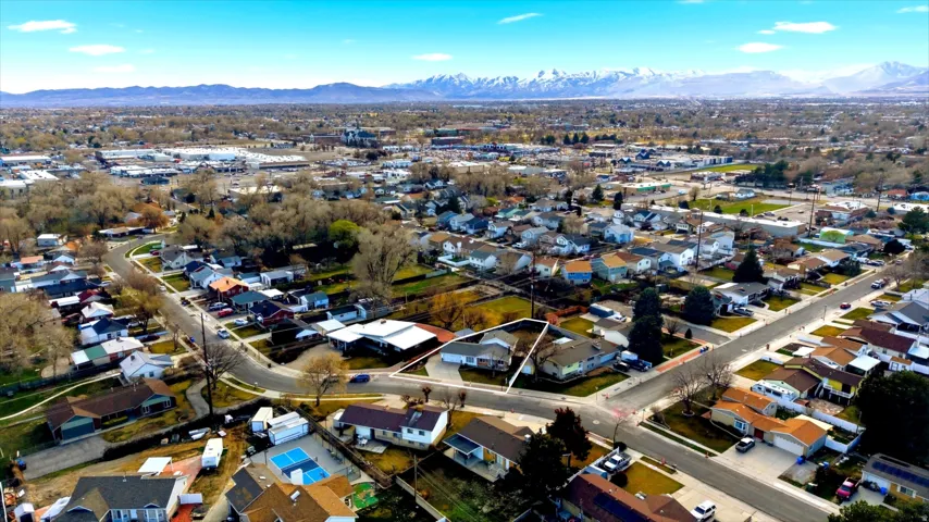 Aerial view of property and surrounding area featuring mountains and nearby suburban area