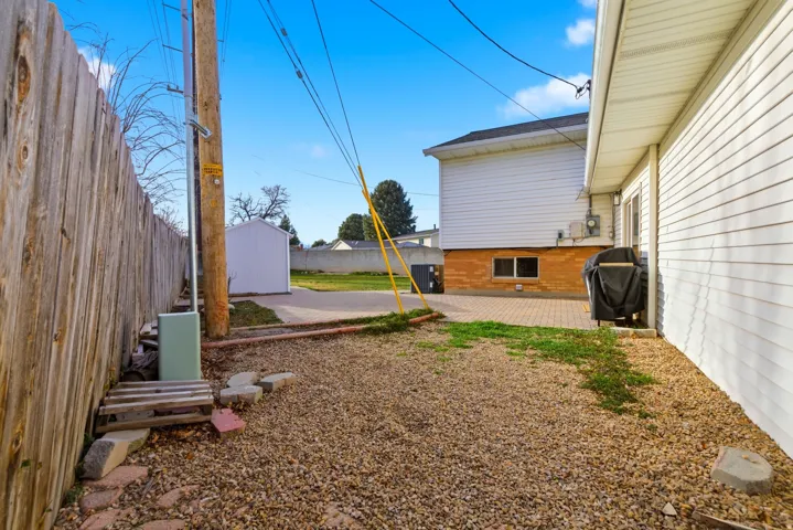 Fenced backyard featuring a shed and a patio