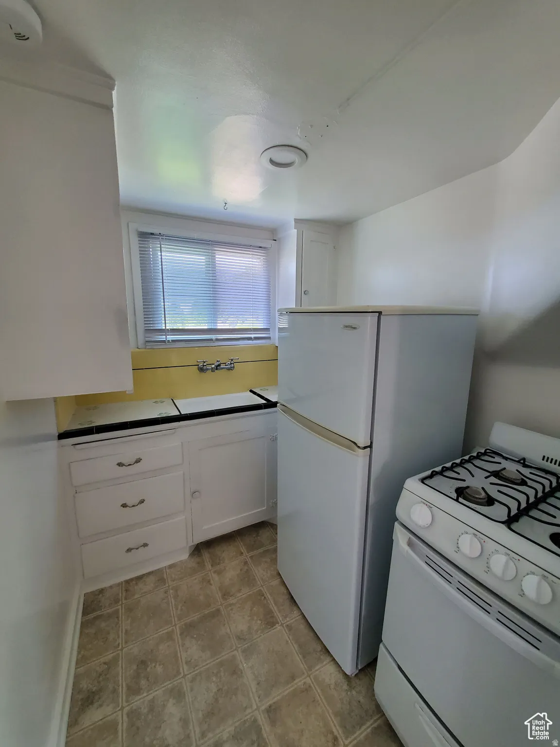 Kitchen featuring custom vintage tile, white gas range oven & fridge and white cabinets