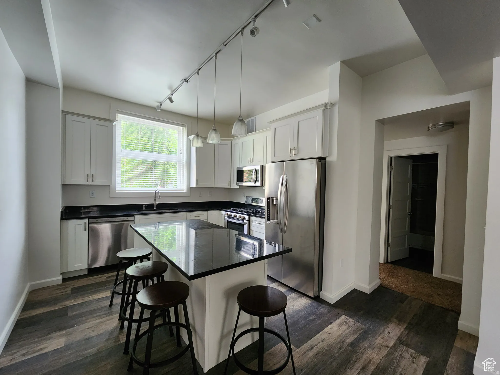 #1 Kitchen featuring counter-bar dining, stainless steel appliances, dark wood-style flooring, a kitchen island, and white cabinets