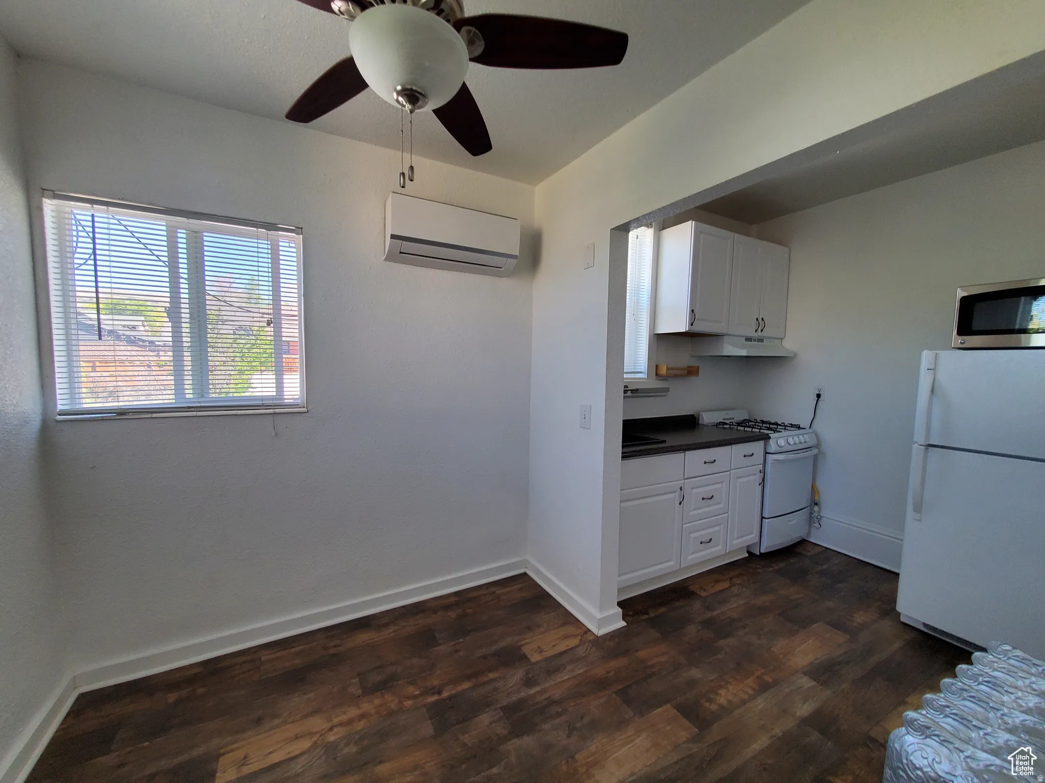 Kitchen featuring white appliances, white cabinetry, dark countertops, and dark wood finished floors, and mini-split A/C & Heat unit