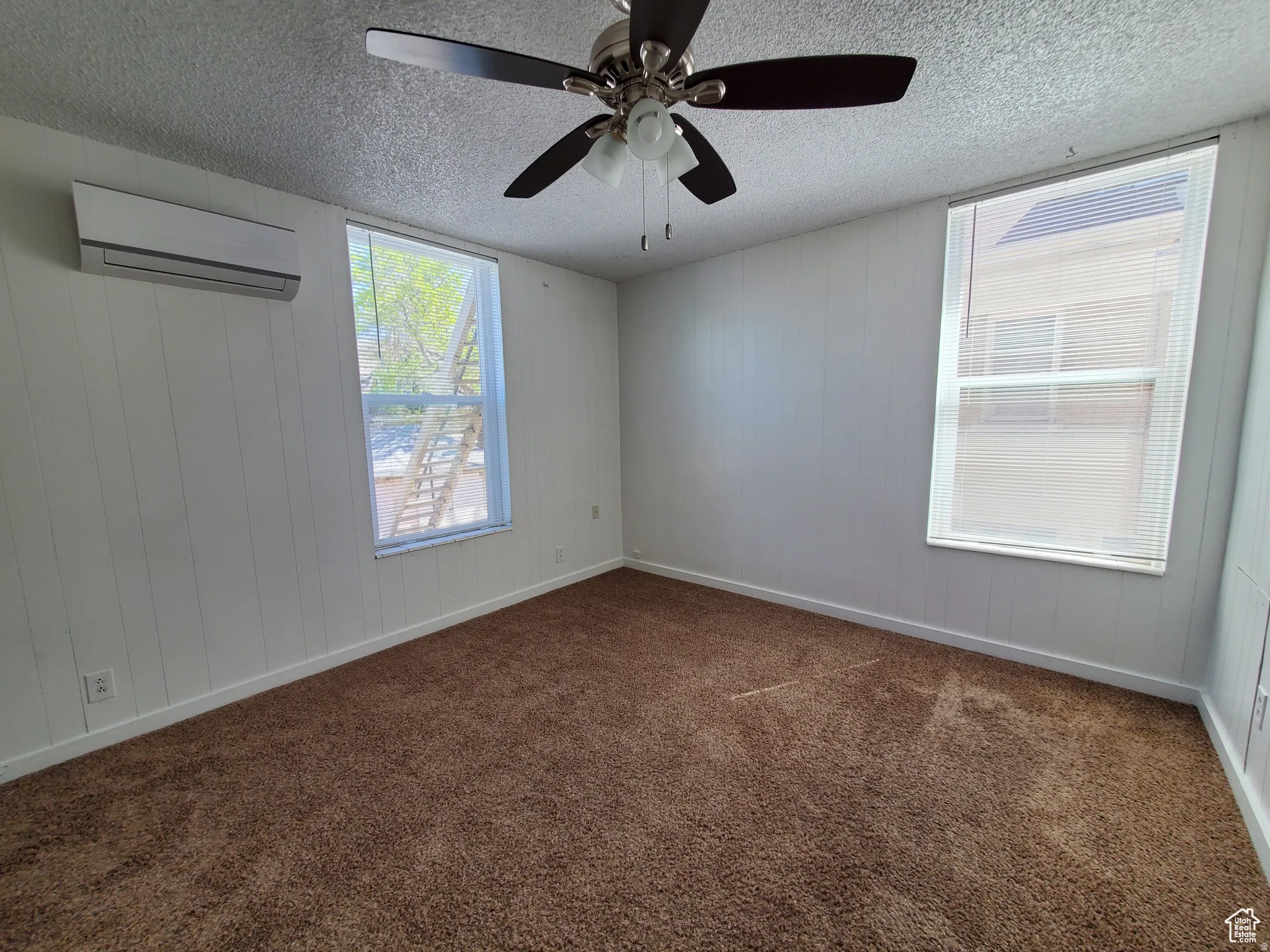 Studio with a ceiling fan, painted wooden walls, and mini-split A/C & Heating unit