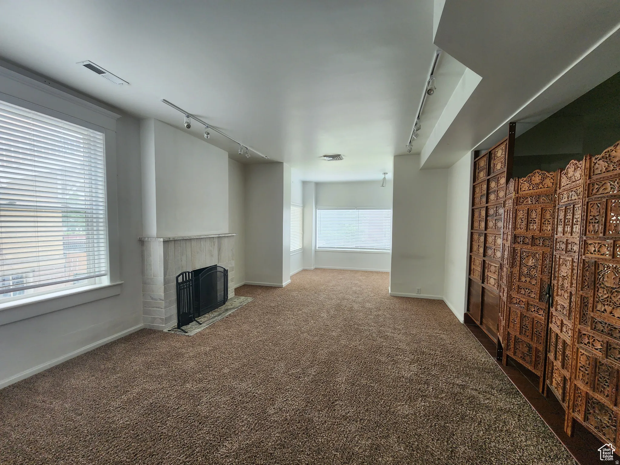 #1 Unfurnished living room with rail lighting, a fireplace with flush hearth, healthy amount of natural light, and dark carpet