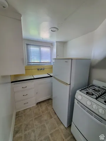 Kitchen featuring custom vintage tile, white gas range oven & fridge and white cabinets
