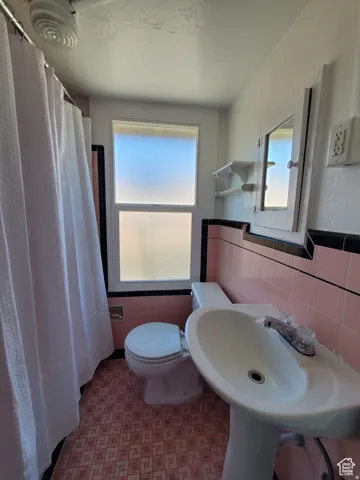 Bathroom with a shower with shower curtain, and custom vintage tile walls