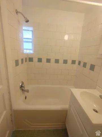 Bathroom featuring vanity and bathtub / shower combination  with custom tile