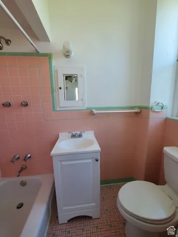 Bathroom featuring vanity, shower / bathtub combination, custom vintage tile walls