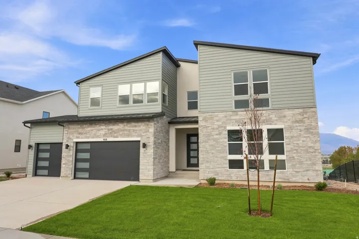 Contemporary exterior featuring stone and horizontal siding, multiple large windows, and a two-car garage with modern frosted glass inserts