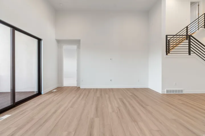 Empty room featuring light wood-type flooring and a high ceiling