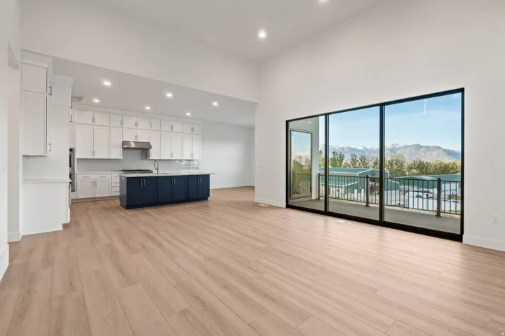 Two tone kitchen with open floor plan, a mountain view, light countertops, a kitchen island with sink, and light wood-style floors