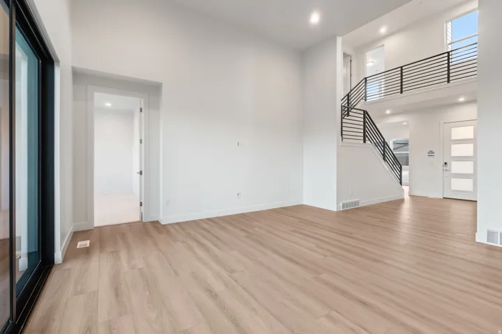 Unfurnished living room featuring a high ceiling, light wood-style flooring, and recessed lighting