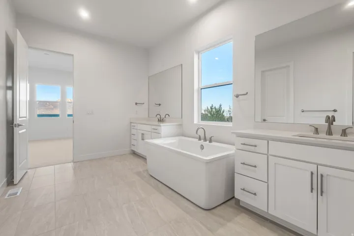 Bathroom featuring two vanities and a freestanding tub