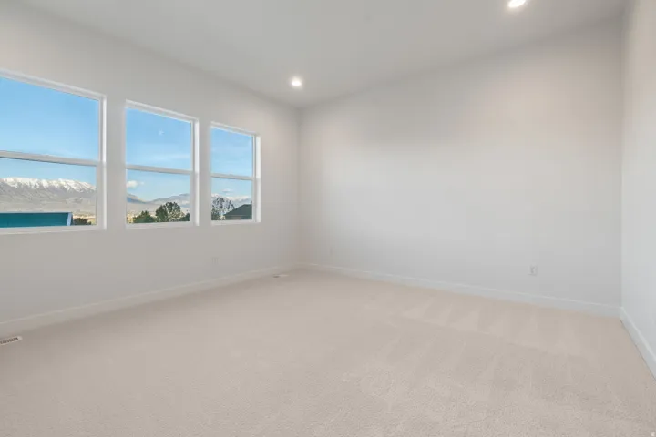 Empty room featuring light carpet, a mountain view, and recessed lighting