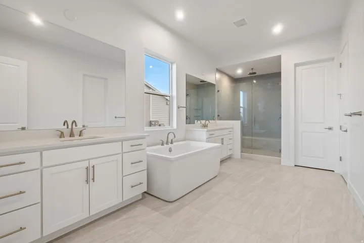 Bathroom featuring two vanities, a shower stall, and a soaking tub