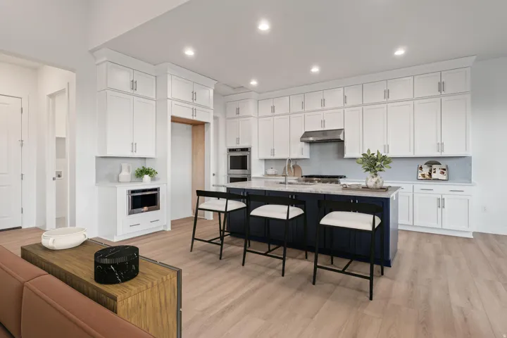 Modern kitchen featuring white cabinetry, a large two-tone island with seating, built-in stainless steel appliances, and light wood-finish flooring