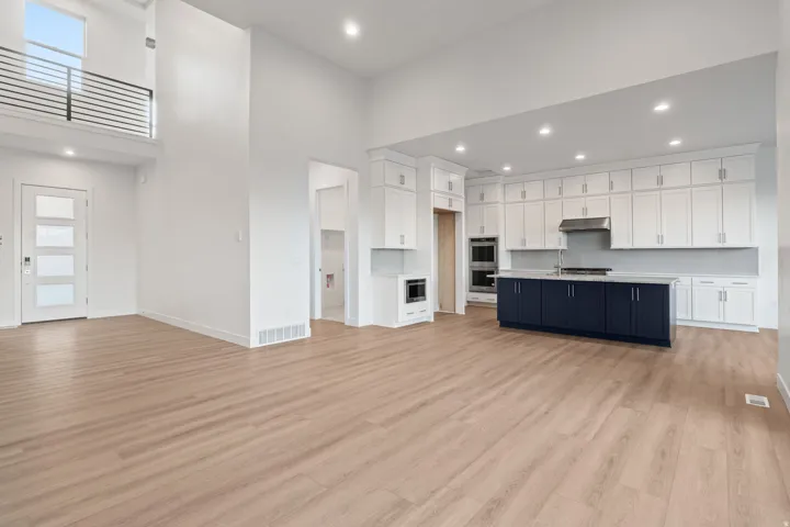 Kitchen with open floor plan, an island with sink, recessed lighting, light countertops, and two tone color scheme