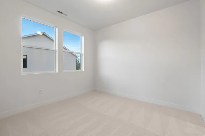 Unfurnished room featuring light carpet and baseboards