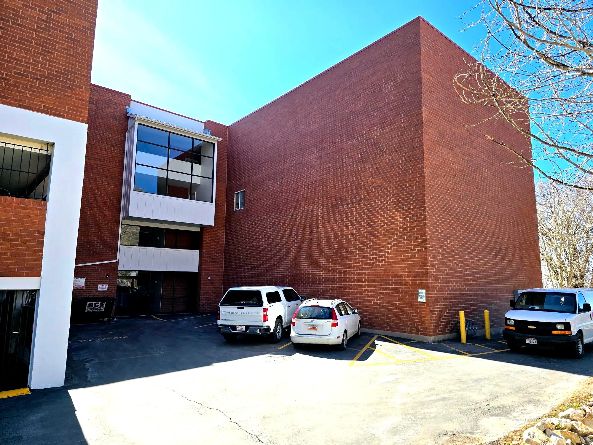 View of building lower level entrance featuring uncovered parking