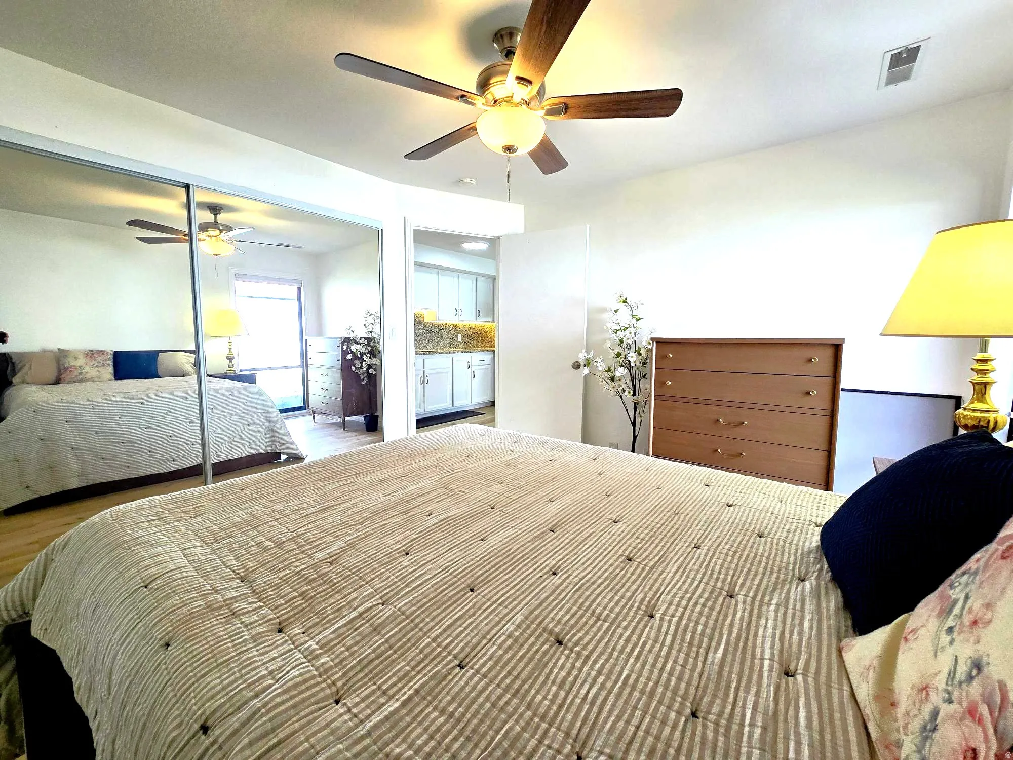 Bedroom featuring ceiling fan, wood finished floors, and a mirrored closet doors.